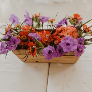 a wooden basket filled with purple and orange flowers